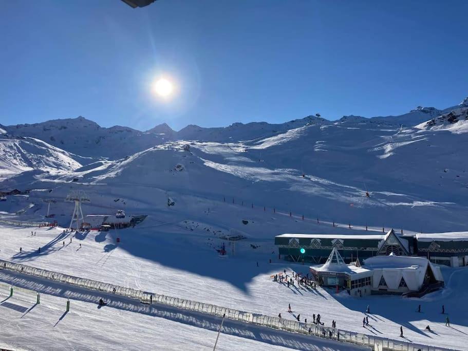 a snow covered mountain with a ski slope with the sun in the sky at Appartement pied pistes à Val thorens in Val Thorens