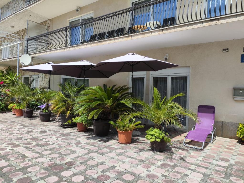 a patio with chairs and umbrellas and potted plants at Villa Niko in Podstrana
