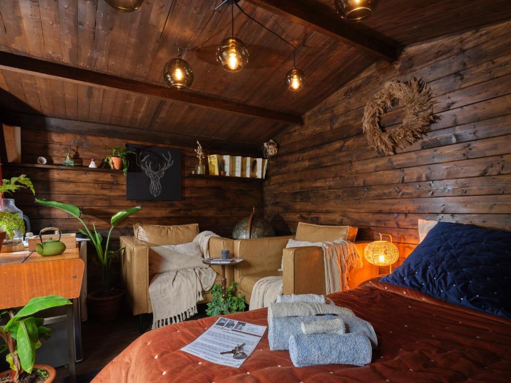 a bedroom with wooden walls and a bed and chairs at La Cabane de l’Explorateur in Cholet