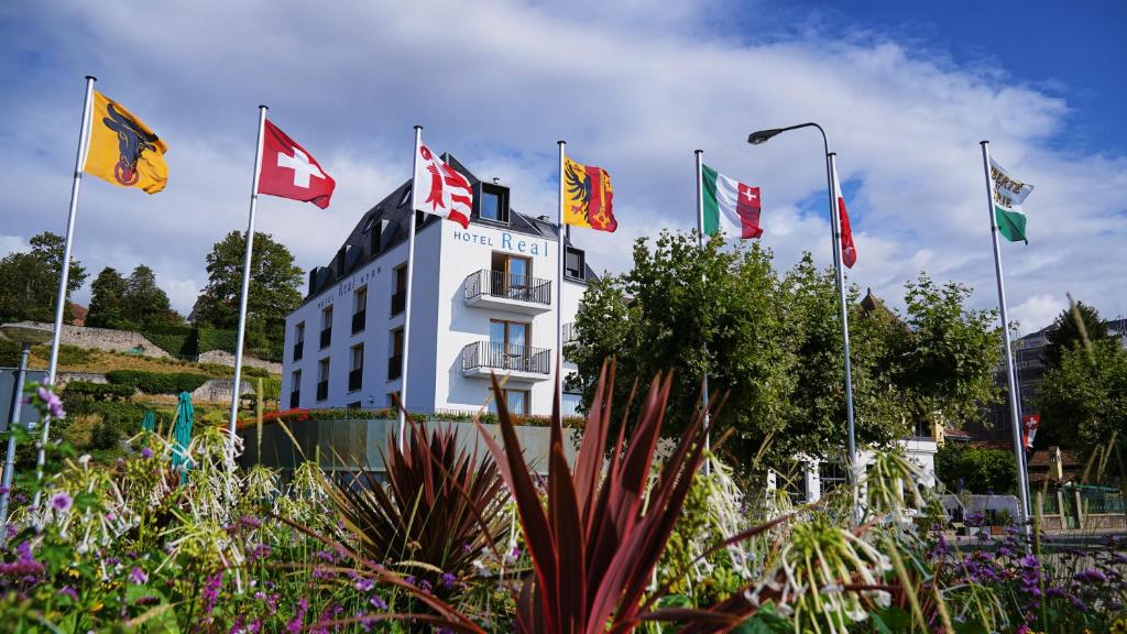un grupo de banderas volando delante de un edificio en Hôtel Real Nyon by HappyCulture en Nyon