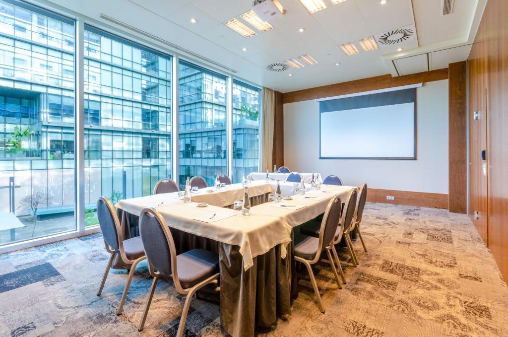 A formal meeting room set around a long table with a projection screen.