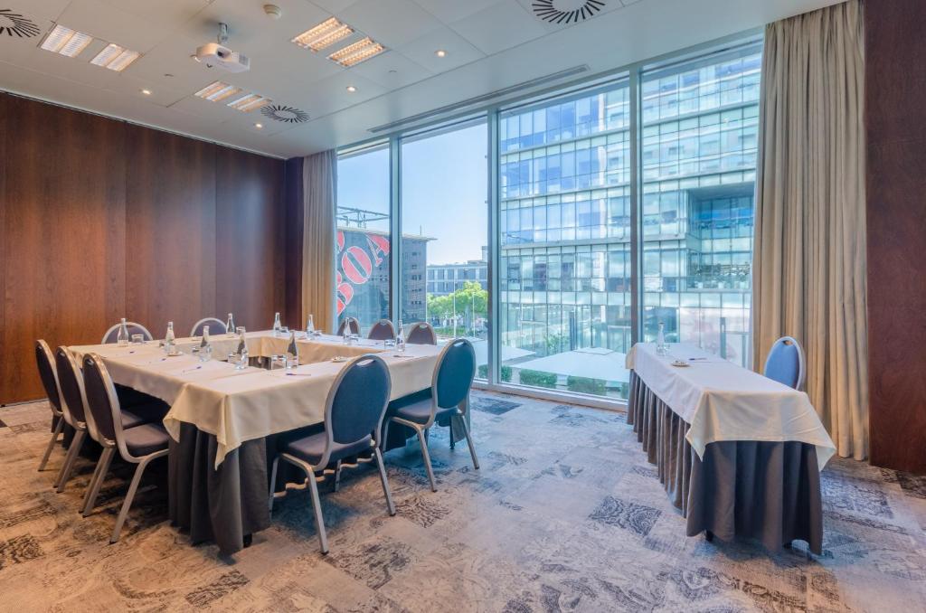 A naturally lit meeting room with a long table and additional catering tables.