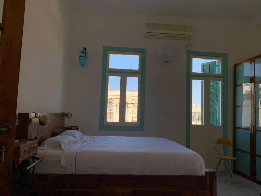 sypialnia z białym łóżkiem i 2 oknami w obiekcie Central, Authentic and Stylish Old Yafo Experience w Tel Awiwie