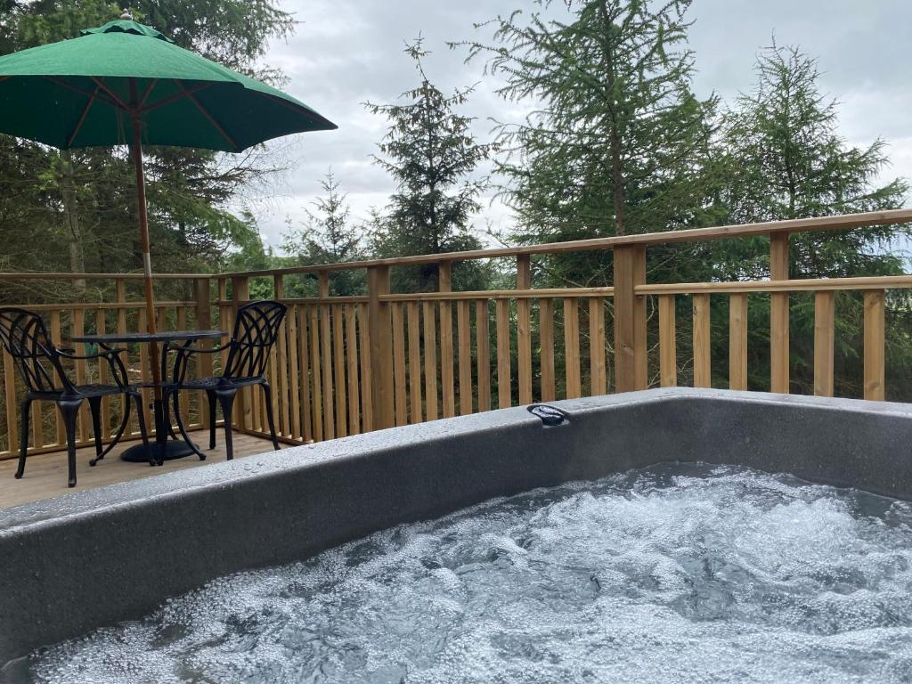 uma banheira de hidromassagem com uma mesa e um guarda-chuva em Conker Lodge with Hot Tub em Cupar