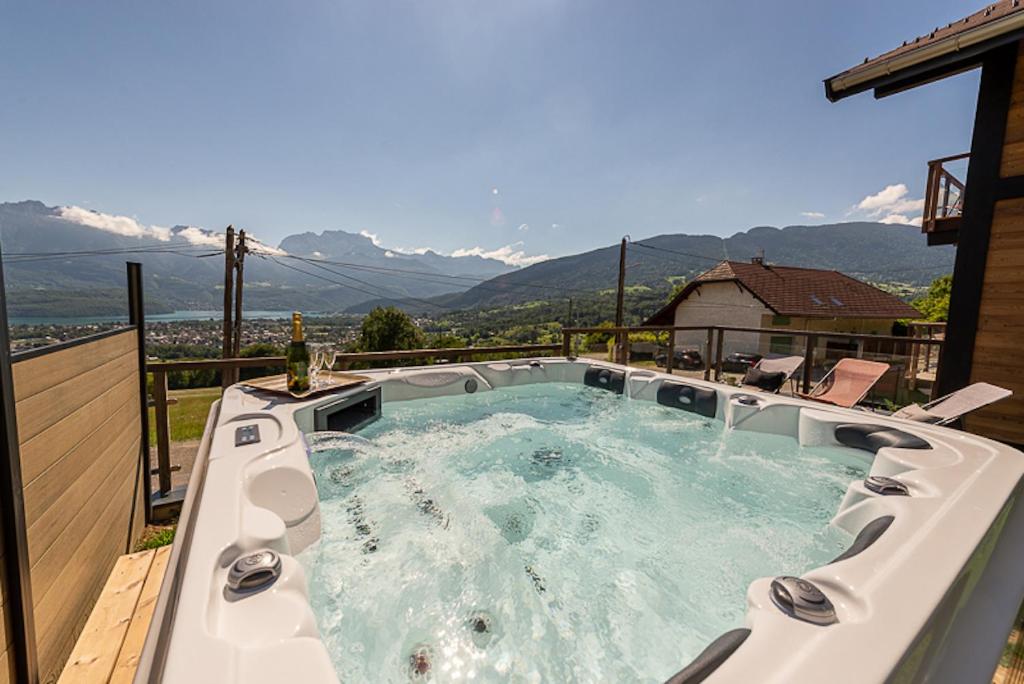 un bain à remous sur une terrasse avec des montagnes en arrière-plan dans l'établissement ANNECY HAPPY LODGE DUPLEX 9 pers, à Saint-Jorioz