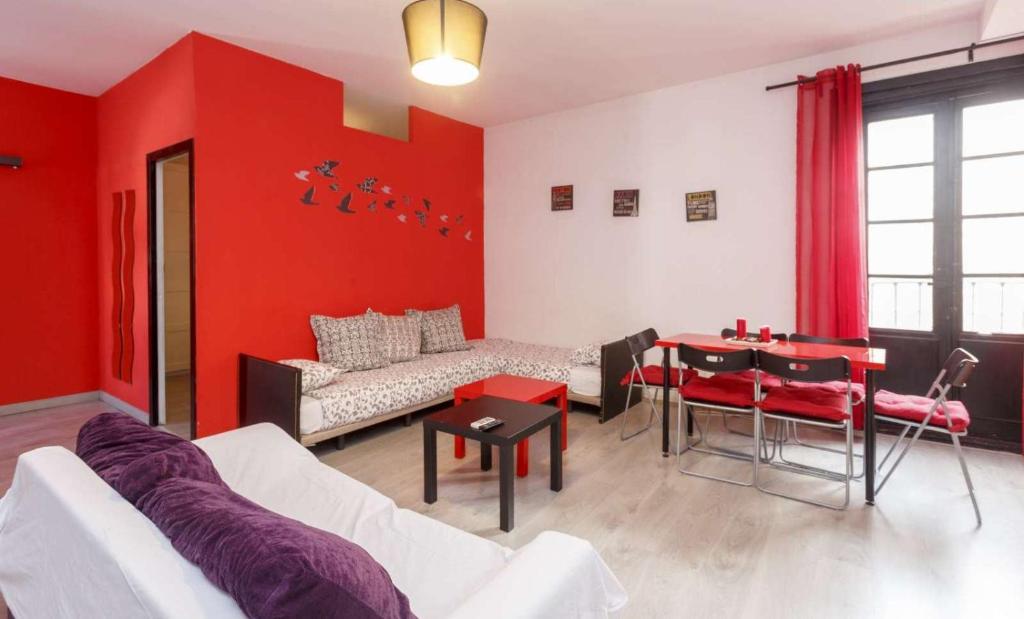 salon z czerwonymi ścianami, kanapą i stołem w obiekcie Desing Puerta del Sol 6 w Madrycie