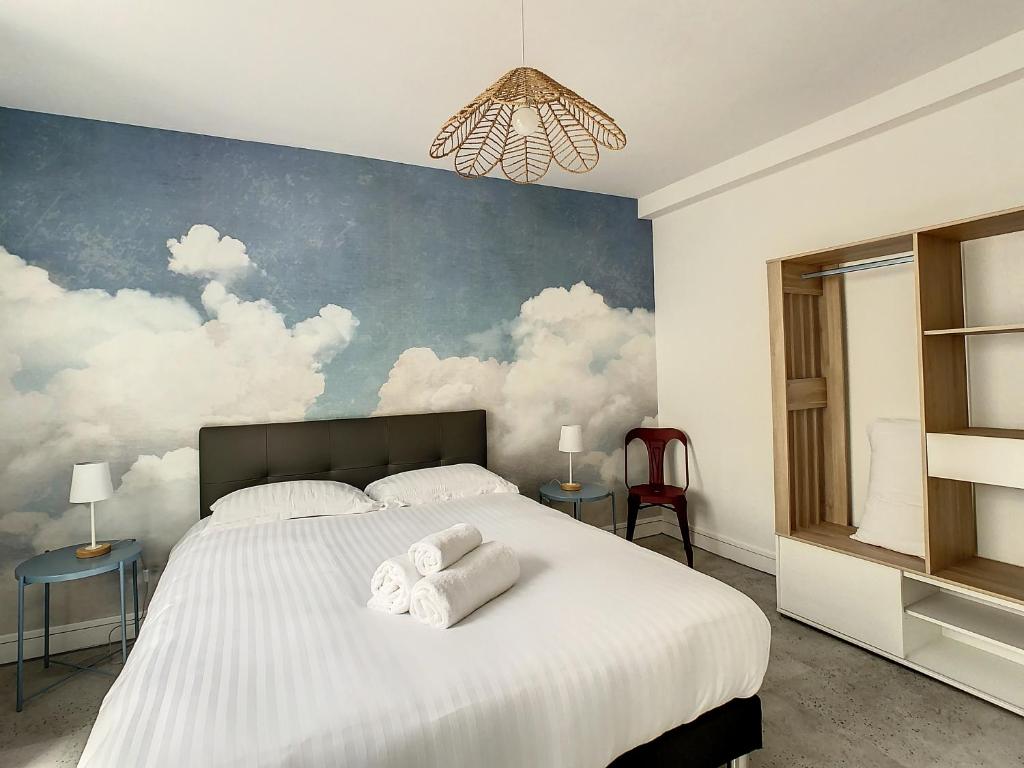 een slaapkamer met een groot bed met wolken op de muur bij Foncillon Plage in Royan