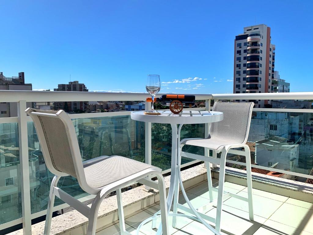 stół i krzesła na balkonie z lampką wina w obiekcie FLAT exclusivo no Hotel RAMADA Macaé, Smartv, Wifi 512Mbps, piscina e Garagem w mieście Macaé