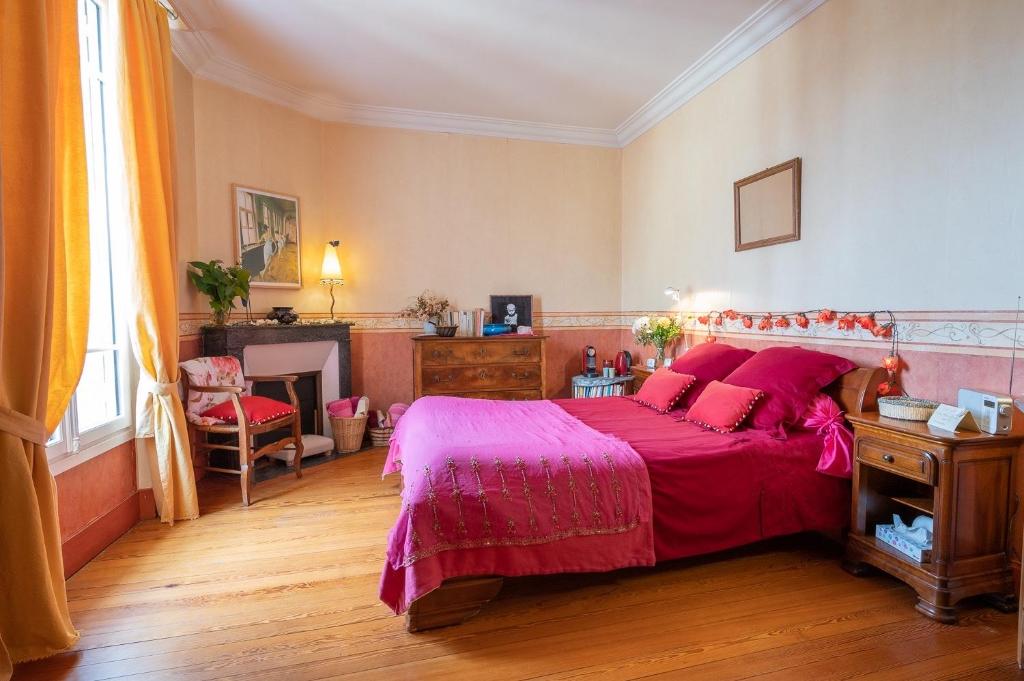 um quarto com uma cama grande e um cobertor rosa em Atelier chez Marie em Carnetin