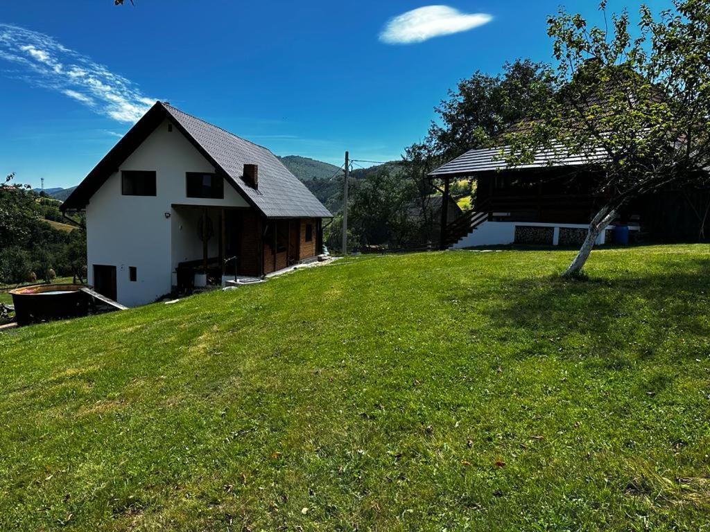 un granero blanco en una colina con césped y una casa en Casa Sufletului en Avram Iancu