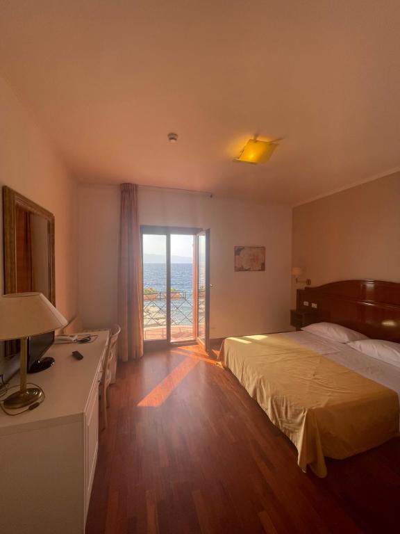 a hotel room with a bed and a sliding glass door at Hotel La Lampara in Reggio Calabria