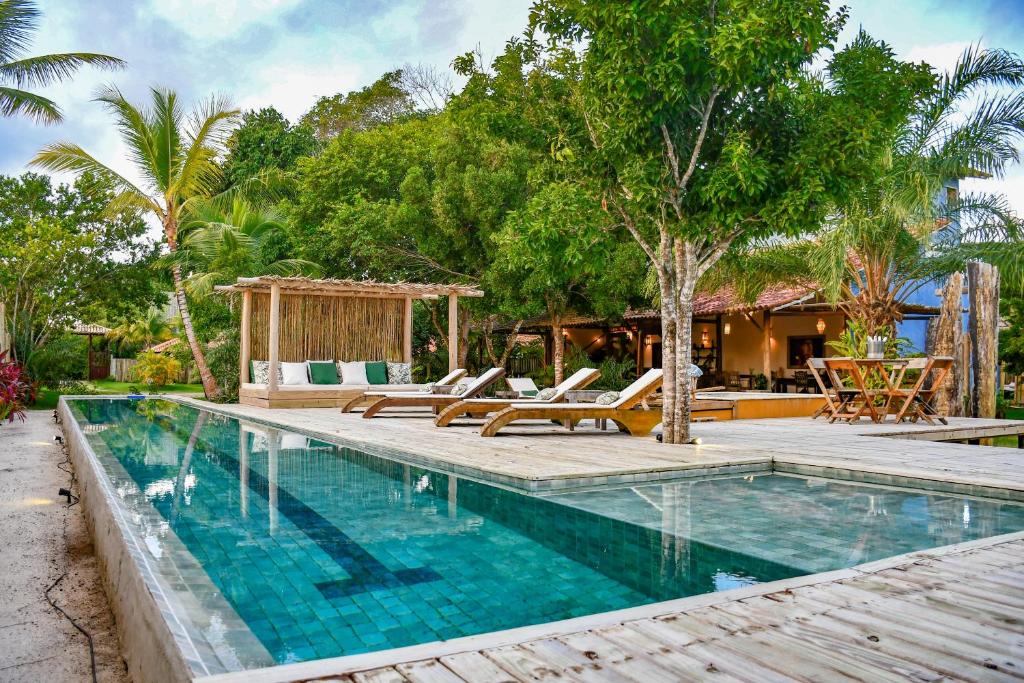 una casa y una piscina al aire libre con tumbonas en Riviera Trancoso, en Trancoso
