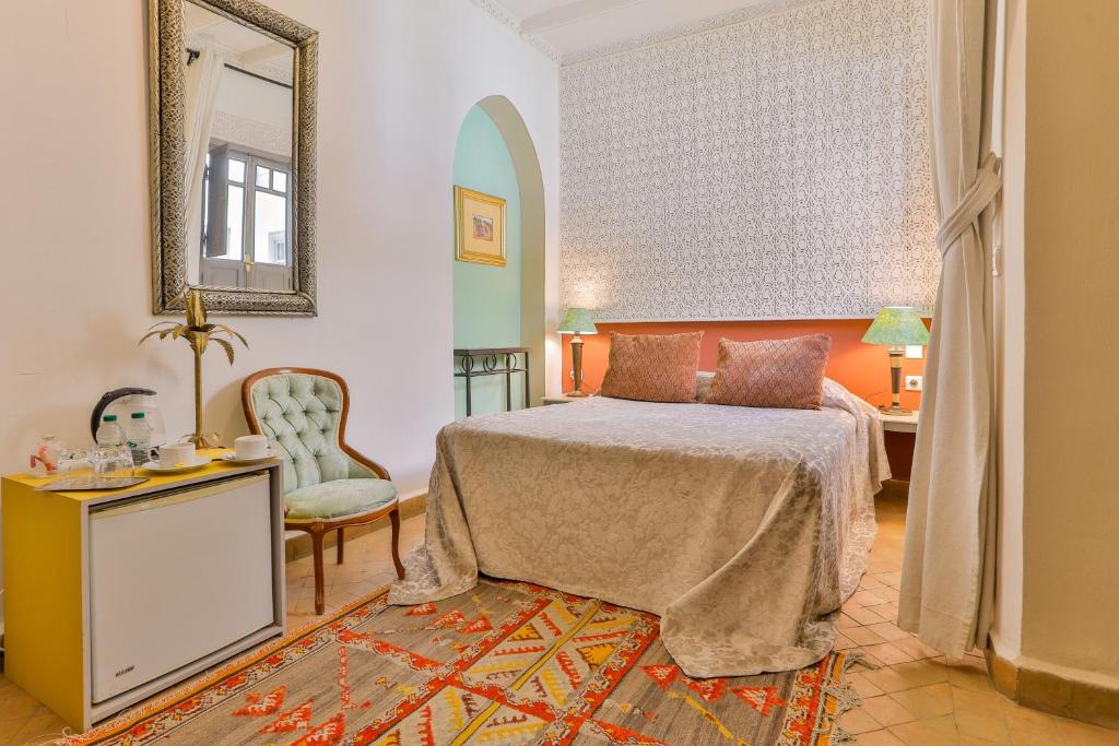 una camera con letto, specchio e sedia di Riad Dar Saad - Hammam & Spa a Marrakech