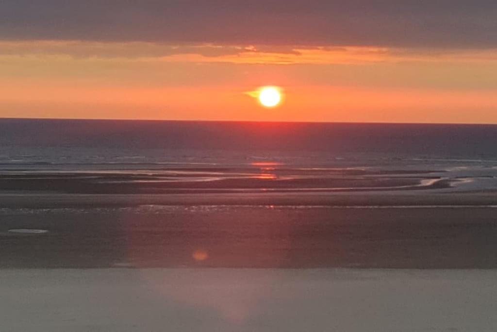 a sunset over the ocean with the sun in the sky at 100 % vue mer, à Berck-sur-Mer in Berck-sur-Mer