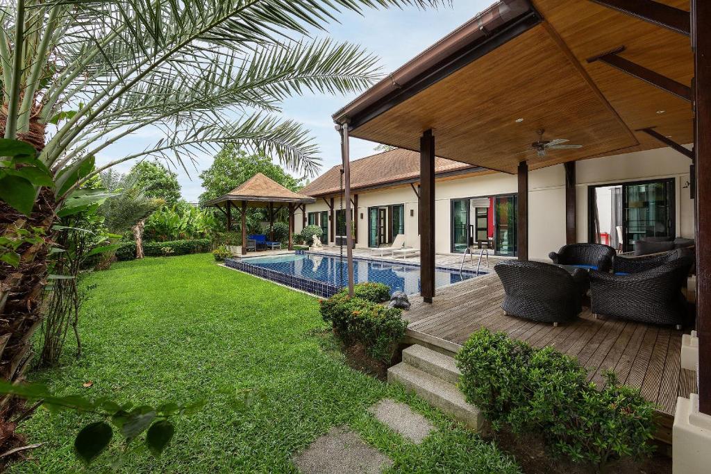 een huis met een houten terras en een tuin bij VILLA MARAMA | Private Pool | Kokyang Estate by Tropiclook | Naiharn beach in Nai Harn Beach