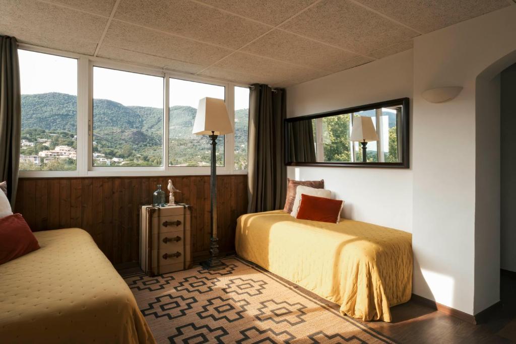 a hotel room with two beds and two windows at Surplage Hotel Cavalière in Le Lavandou