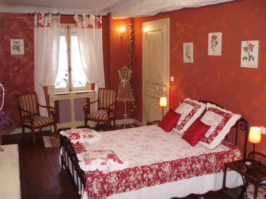 um quarto com uma cama com paredes vermelhas em LA BOUILLOIRE, demeure historique et de caractère du 19è siècle. em La Bouille