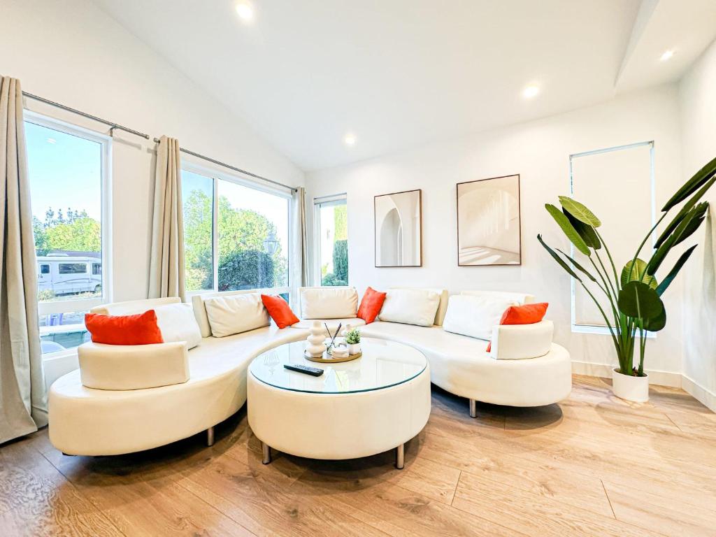 una sala de estar con muebles blancos y ventanas grandes. en Modern 2BR Oasis - Cal-Cal, en Calabasas