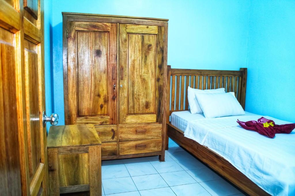 a small bedroom with a bed and a wooden door at KJ Purple House Senggigi in Senggigi