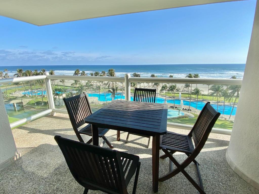 einen Tisch und Stühle auf einem Balkon mit Strandblick in der Unterkunft Mayan Playa Departamento Uxmal in Acapulco