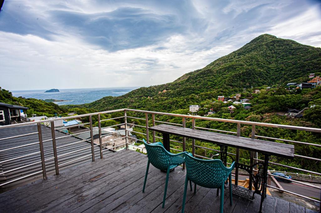 uma mesa e duas cadeiras num deque com uma montanha em Shabby Home 28 em Jiufen
