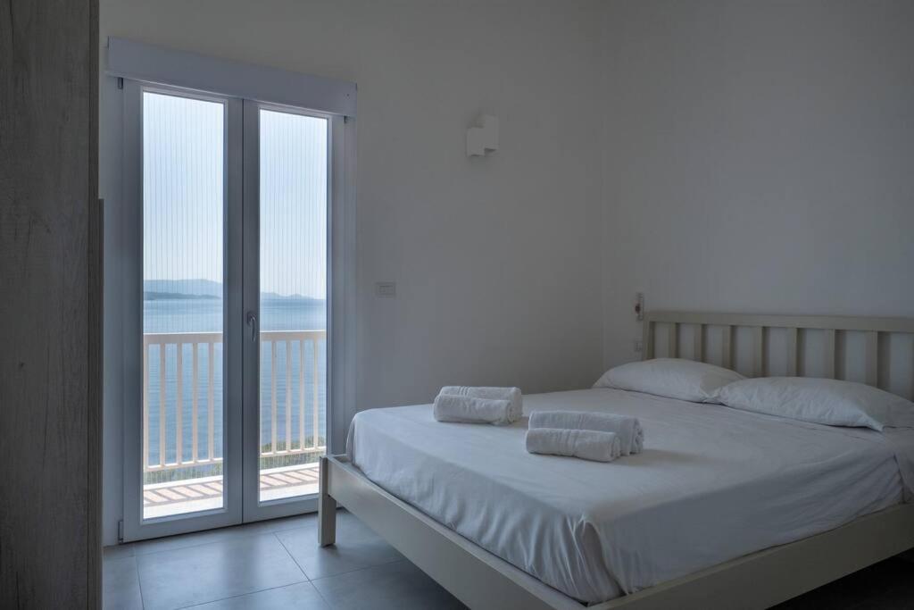 Villa Fertilia 8 posti letto - Key to Villas في فيرتيليا: غرفة نوم مع سرير وإطلالة على المحيط