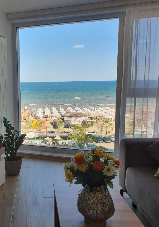 a living room with a large window with a view of the beach at Alee Infinity Pool & Spa in Mamaia Sat/Năvodari