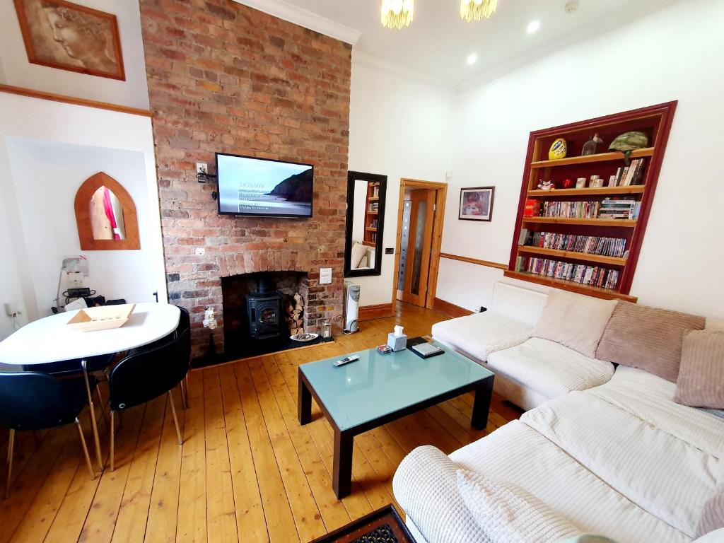 a living room with a couch and a table and a fireplace at F1 MAISON 108 - Holiday Home - Full Kitchen - Street FREE PARKING, NETFLIX - 68Mbps BT WIFI - DVD's - Welcome Tray - By Corner from Gavin n Stacey Film House in Barry