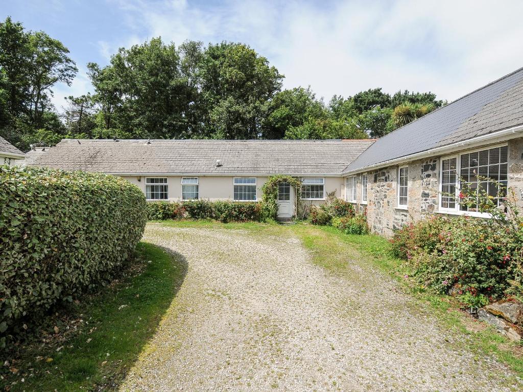 a stone house with a gravel driveway in front of it at Forge Cottage in Helston