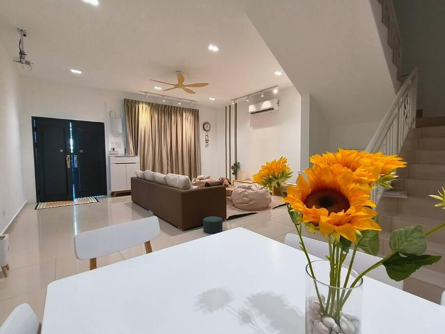 ein Wohnzimmer mit einem Tisch und einer Vase aus Sonnenblumen in der Unterkunft SecreteGarden627 3 storey 5r4b PartyHome 12-20pax in Malakka