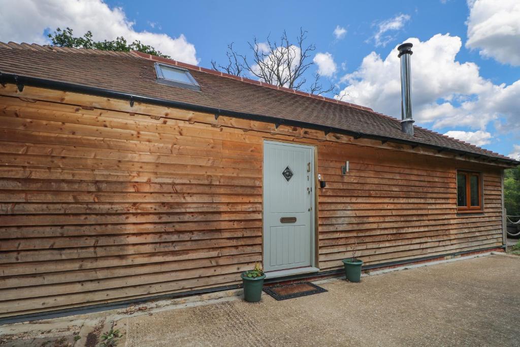 un edificio de madera con una puerta blanca en Garden Cottage en Farnham