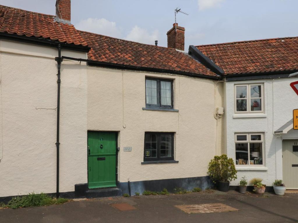 uma casa com uma porta verde numa rua em Damson Cottage em Bridgwater