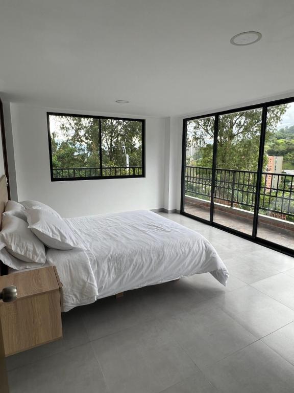 a white bedroom with a bed and large windows at Casa campestre en el corazón de envigado in Envigado