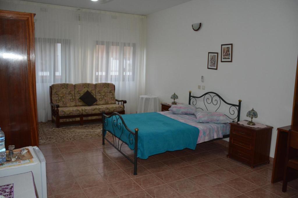 um quarto com uma cama e um sofá em Residencial Chez Flor em Porto Novo