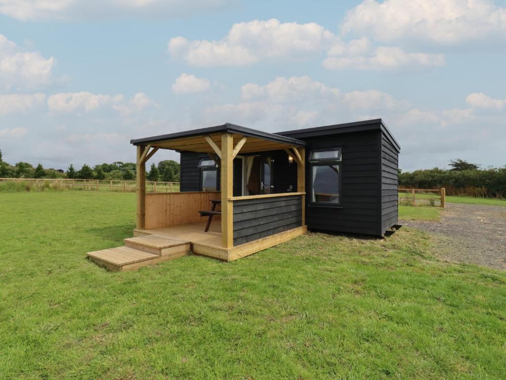 a black tiny house with a gazebo in a field at River Lodge in Aldeburgh