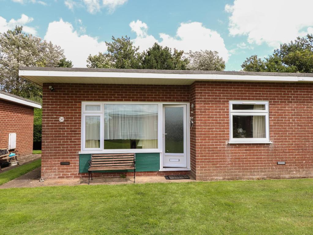 a brick house with a bench in a yard at 31 Siesta Mar Chalet Park in Norwich