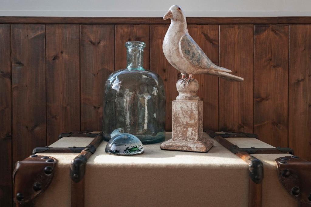 a bird sitting on top of a table with a glass bottle at Surplage Hotel Cavalière in Le Lavandou