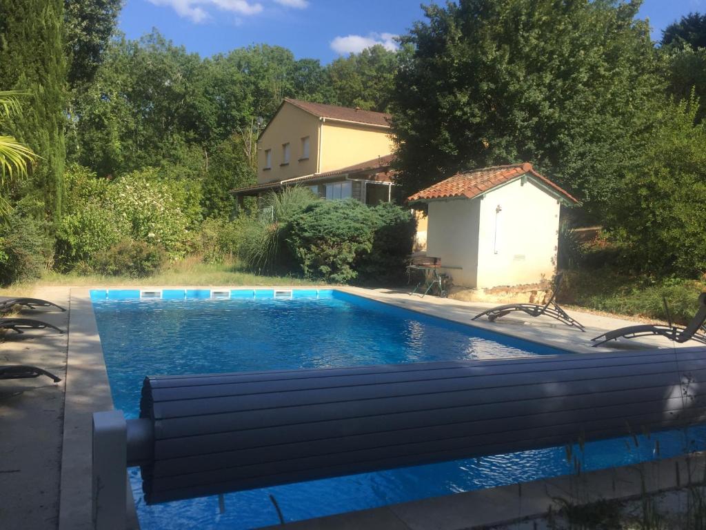 una piscina con un banco frente a una casa en GITES DU MOULIN A VENT, en Le Buisson de Cadouin