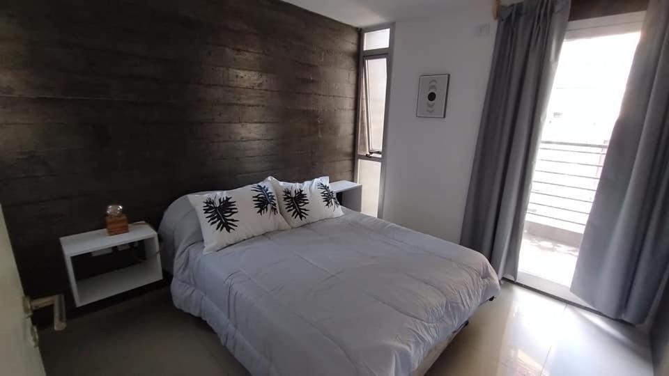 a bedroom with a white bed with a wooden wall at Marcos Paz 100 in San Miguel de Tucumán