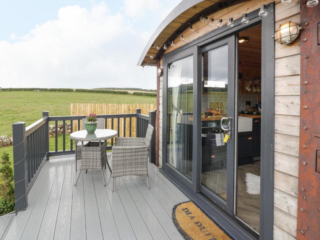 una terraza de madera con mesa y sillas. en Greenacres Carriage, en Maybole