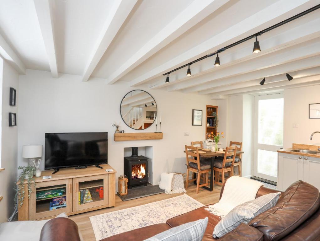a living room with a fireplace and a tv at Bwthyn Lili Lily Cottage in Cemaes Bay