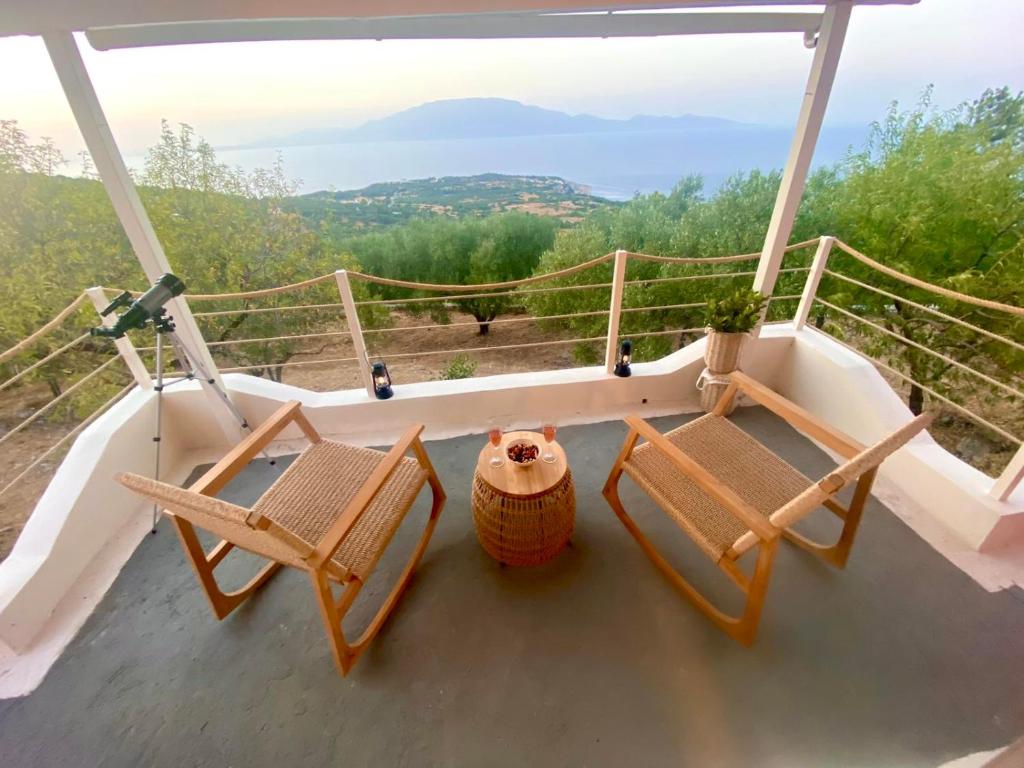 two chairs and a table on a balcony with a view at Coralina Cottage in Koríthion