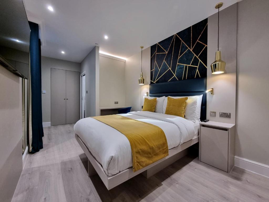 een slaapkamer met een groot bed en een gele deken bij NOX Kensington Gardens in Londen
