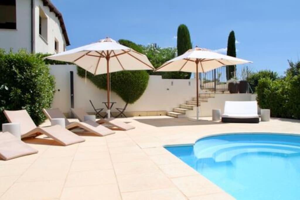 a patio with chairs and umbrellas and a pool at Villa Linnazello - elegant pool villa with sea view near Rome/Tuscany in Tarquinia