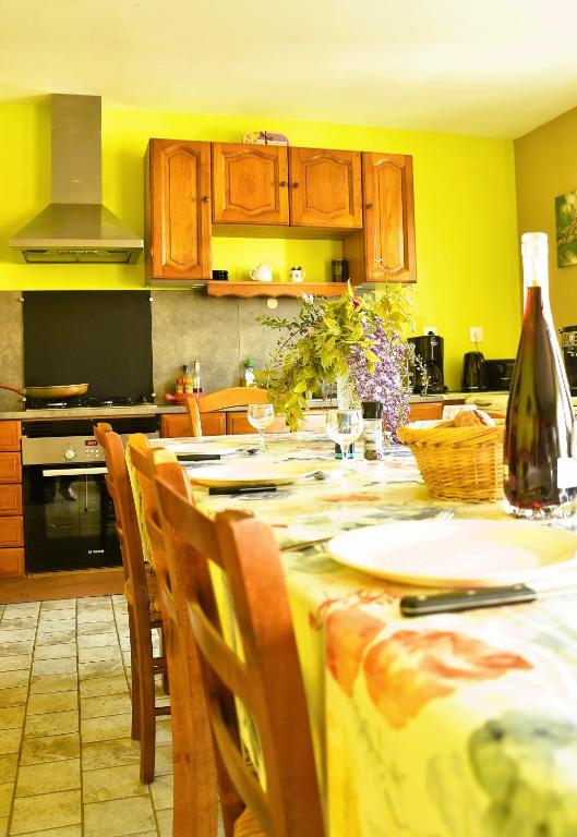 une cuisine avec une table avec des chaises et une cuisine avec des murs jaunes dans l'établissement GRAND LOGIS DES CHOUETTES, 5 chambres, proche de Verdun et ses sites de la grande guerre, à Châtillon-sous-les-Côtes