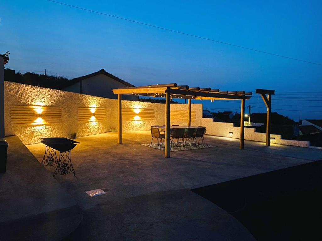 un patio con mesa y dosel por la noche en Casa da Fonte - Alojamento Local com Jacuzzi, en Nordeste