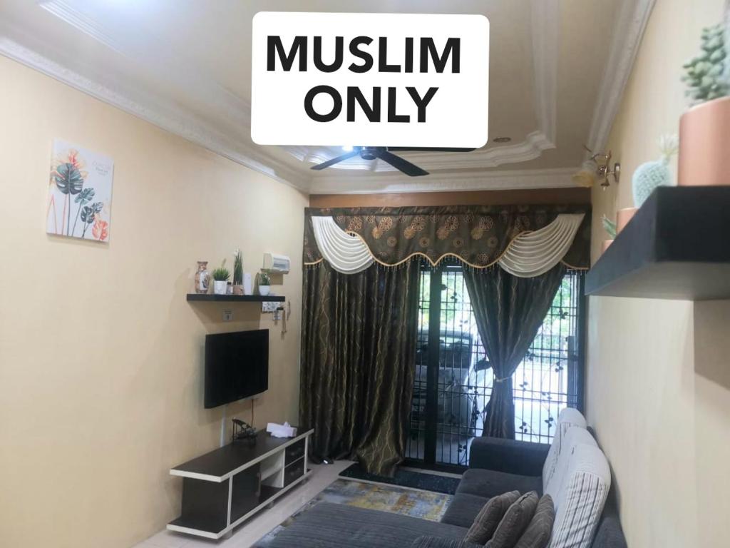 a living room with a couch and a tv at Homestay Taman Lagenda Padang Serai in Padang Serai