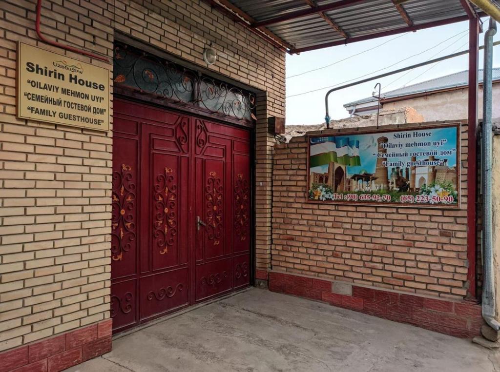 zwei rote Türen an der Seite eines Backsteingebäudes in der Unterkunft Shirin House Guest House in Buxoro