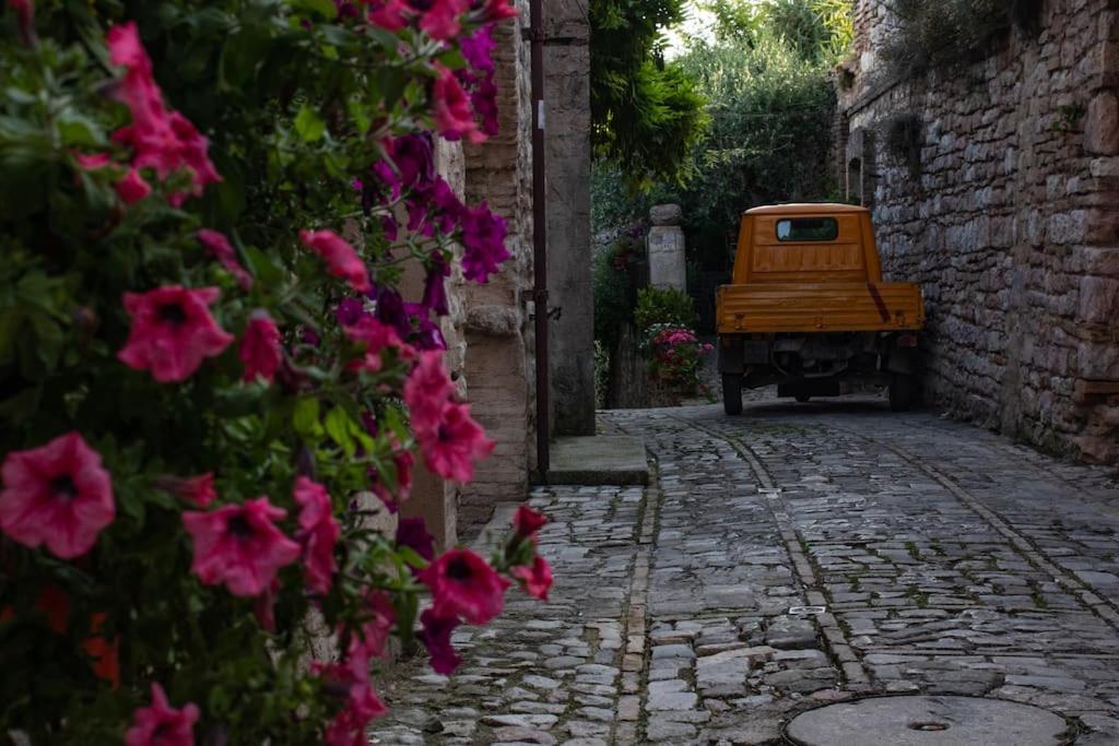 eine Gasse mit rosa Blumen und einem gelben Truck in der Unterkunft La Casa di Agnese in Spello