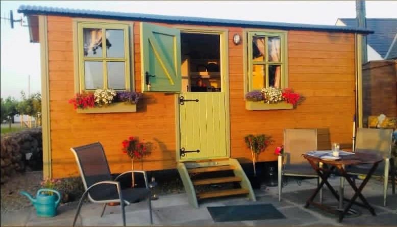 a small house with a table and chairs in front of it at Mountain View Shepherds Hut in Kilkeel